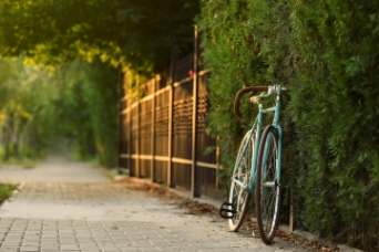 A vintage bicycle leaning against a fence on a paved path, symbolizing the active and eco-friendly lifestyle within residential projects in Bangalore by Mana Projects, amidst lush green surroundings.