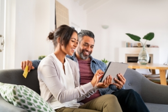 Happy couple reviewing luxury apartments projects in Bangalore on a tablet, symbolizing the modern home-buying experience with Mana Projects.